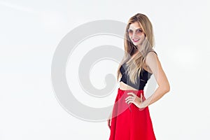 Young blond model presenting new fashionable summer look, wearing circle sunglasses, red skirt and black sleeveless top