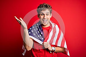Young blond patriotic man with curly hair wearing USA flag celebrating independence day very happy and excited, winner expression