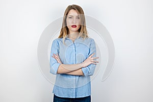 Young blond serious woman looks resolute with her hands one one another standing on  white background