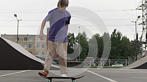 Young blond teenager skater skateboarder man doing 360 kickflip heelflip flip trick jump, ollie, on skateboard in skate