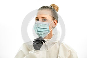 Young blond woman adjusts surgical mask on her face