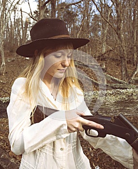 Young blond woman checking a shotgun