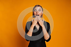Young blond woman covering her mouth while expressing surprise