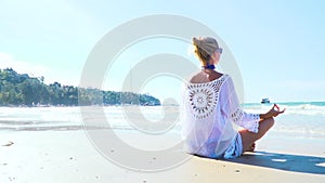 Young blond woman doing yoga on the beach