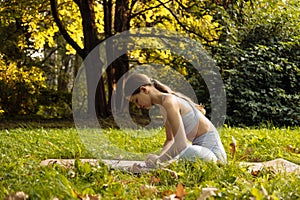 Young woman doing yoga exercise outdoor in the park, sport yoga concept