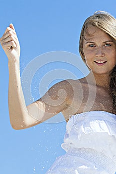 Young blond woman dropping sand from clenched fist