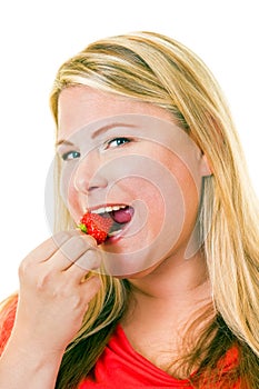 Young blond woman eating strawberry