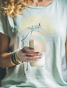 Young blond woman holding bottle of dairy-free almond milk