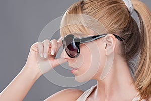 Young blond woman holding modern sunglasse photo