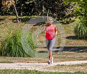 Young blond woman jogging and listening to music in park