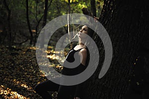 Young blond woman leaning on tree
