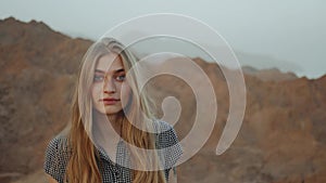 Young blond woman in long dress walks on top of mountain. Mountain landscape with sunset, 4k