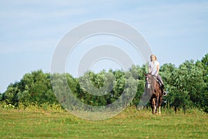 Young blond woman with long hair jockey rider jumping on a bay horse