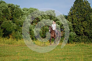 Young blond woman with long hair jockey rider jumping on a bay horse