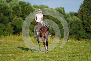 Young blond woman with long hair jockey rider jumping on a bay horse