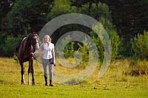 Young blond woman with long hair jockey rider jumping on a bay horse