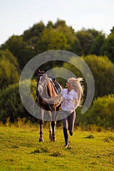 Young blond woman with long hair jockey rider jumping on a bay horse