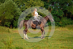 Young blond woman with long hair jockey rider jumping on a bay horse