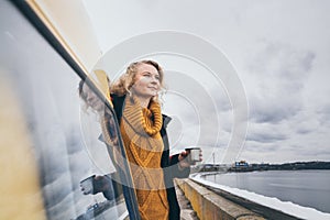 Young blond woman looking out of camper van overlooking the sea