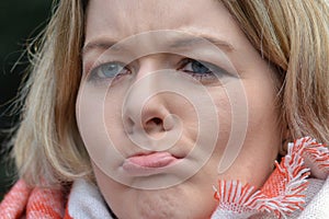 Young blond woman pursing her mouth sceptical