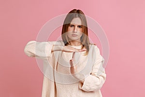 Young blond woman showing time out gesture, looking with strict expression, deadline.