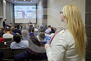 Young blond woman stands in the back of auditorium photo