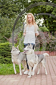 Young blond woman with two dogs Husky on dog-leads