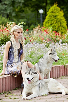 Young blond woman with two dogs Husky sits on low