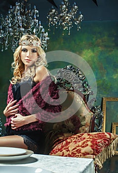 Young blond woman wearing crown in fairy luxury interior with em