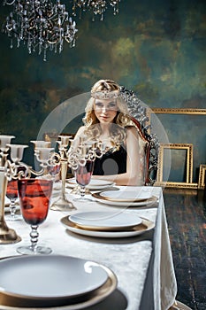 Young blond woman wearing crown in fairy luxury interior with empty antique frames total wealth