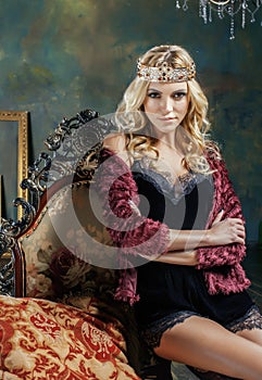 Young blond woman wearing crown in fairy luxury interior with empty antique frames total wealth, magic rich concept