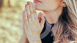 A young blonde 18 year old girl prays with folded hands.