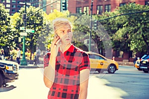 Young blonde American Man talking on cell phone outside in New York City