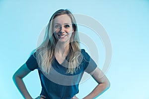 young blonde attractive nurse without a mask posing in front of a camera light blue background medium shot hospital