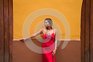 Young, blonde, beautiful woman in a red dress is visiting seville. The woman is posing for the camera very elegant for the photos