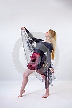 Young blonde blue-eyed dancer woman in fantasy dress on white background