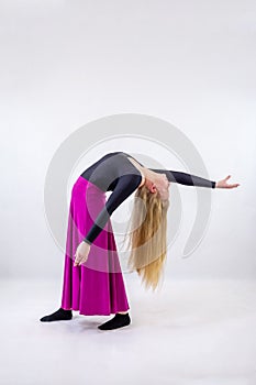 Young blonde blue-eyed dancer woman in long purple skirt on white background