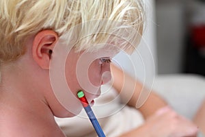 Young blonde boy doing homework with pencil