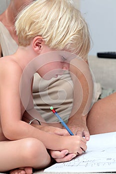 Young blonde boy doing homework with pencil