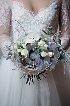 A young blonde bride in white wedding dress on a background of white walls and white tree in the background