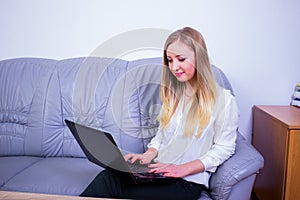 Young  blonde business woman sitting on the couch with notebook in the office