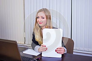 Young blonde businesswoman with modern gray laptop in the office