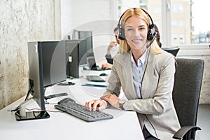 Young blonde call center operator woman at workplace.