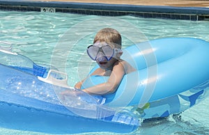 Young blonde caucasian boy using two floats in swimming pool