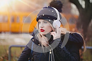 Young blonde caucasian woman listening music by headphones outdo