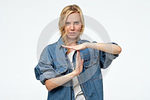 Young blonde caucasian woman showing time out sign over white background.