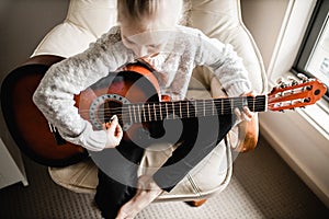 A young caucasion girl practicing playing her guitar photo