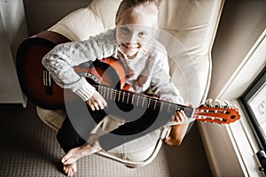 A young caucasion girl practicing playing her guitar photo