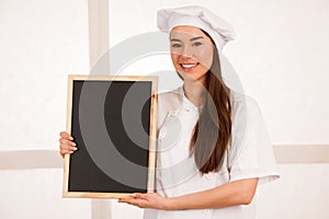 Young blonde chef woamn holds kitchenware as she prepares to coo