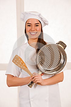 Young blonde chef woamn holds kitchenware as she prepares to coo